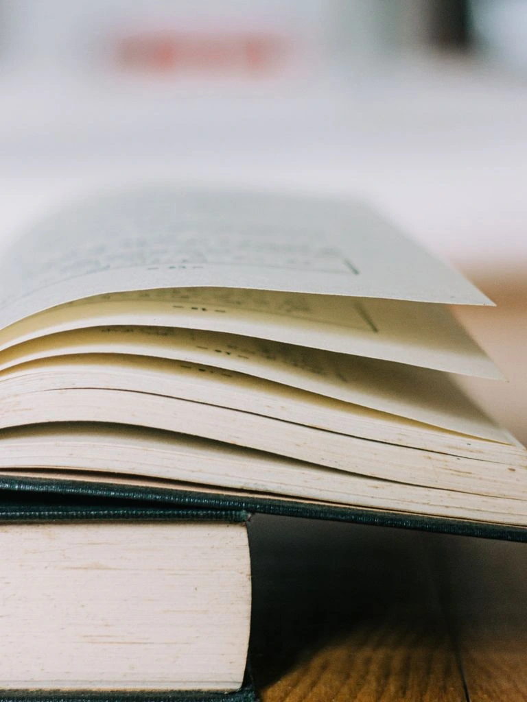 كتاب استراتيجيات العلامات التجارية مفتوح على مكتب رخامي داكن مع إضاءة ذهبية جانبية